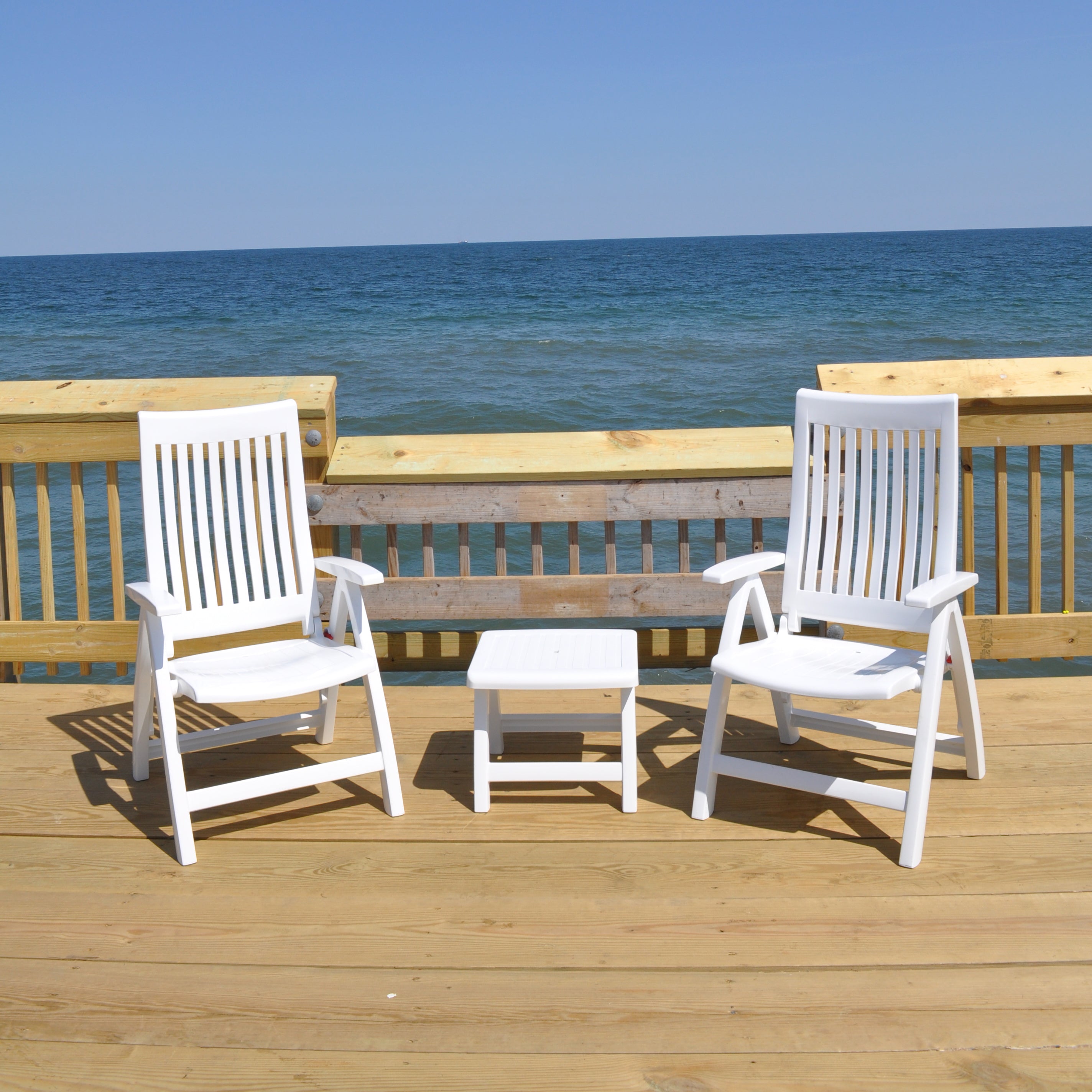 Roma 3-Piece Lounge Set with Cushions showing white resin chairs and side table on wooden deck by the ocean.