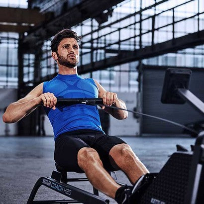 Lifestyle image of the Coach H20 rowing machine with man in an industrial setting using the rower.